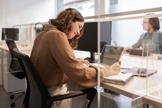 Professional woman working in coworking office with divider