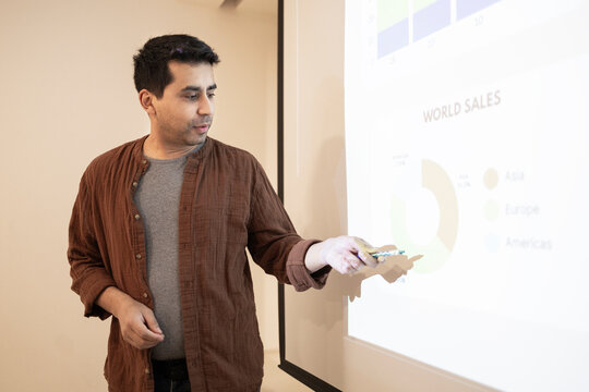 Business presenter pointing at world sales chart on screen
