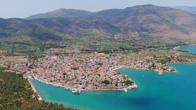 Aerial view of the picturesque seaside town of Galaxidi in the Peloponnese, Greece, showcasing its beautiful bay with turquoise water, traditional houses, and surrounding green hills