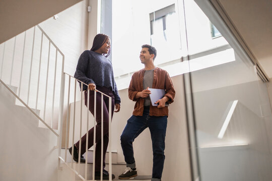 Coworkers chat on office stairs in modern coworking space