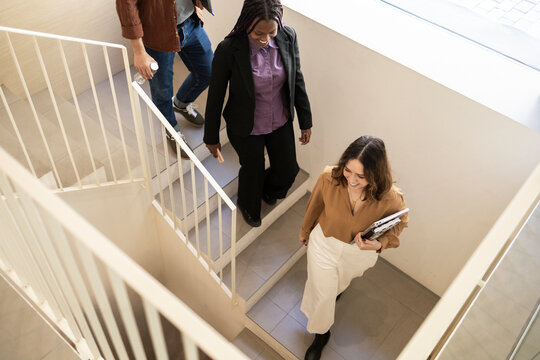 Coworking team walking downstairs in modern office stairwell