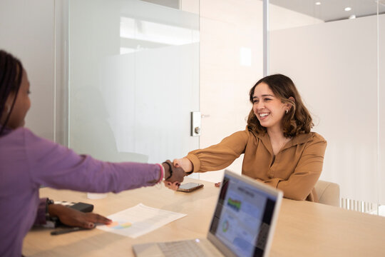 Businesswomen shaking hands in modern office meeting