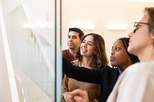 Team brainstorming in coworking office with glass whiteboard