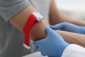Obraz premium Nurse palpating patient's vein before drawing blood sample at table in clinic, closeup