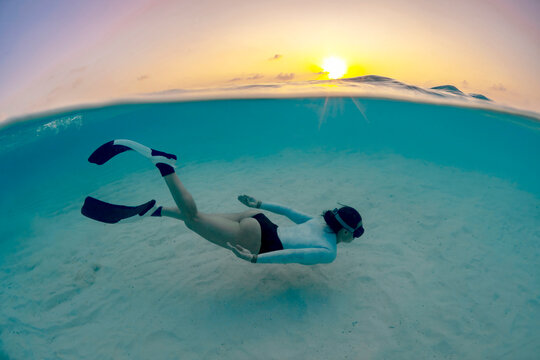 Diver exploring thila reef at sunrise in clear lagoon