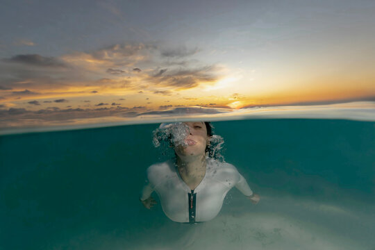 Split view scuba diver exploring a thila at sunset