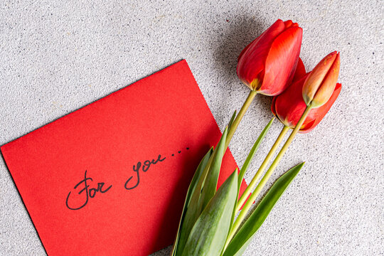 Red tulips with card on a textured surface