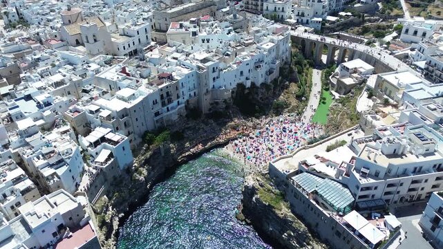 Drone aerial footage of Polignano a Mare historic coastline and Lama Monachile beach with turquoise Adriatic Sea in Puglia, southern Italy.