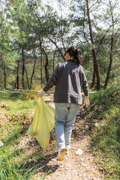 Volunteer collecting litter on forest trail for cleanup
