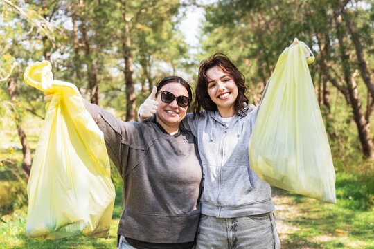 Mother and daughter volunteers cleaning nature in community
