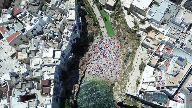 Drone aerial footage of Polignano a Mare historic coastline and Lama Monachile beach with turquoise Adriatic Sea in Puglia, southern Italy.