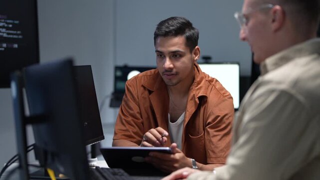 ortrait of a smiling young software developer discussing programming solutions and artificial intelligence parameters with a senior IT consultant.