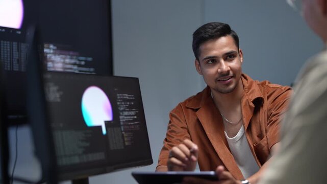 ortrait of a smiling young software developer discussing programming solutions and artificial intelligence parameters with a senior IT consultant.