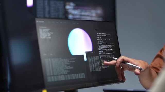 Close up of a technology developer hand pointing a stylus at a computer screen to debug machine learning scripts and artificial intelligence logic.