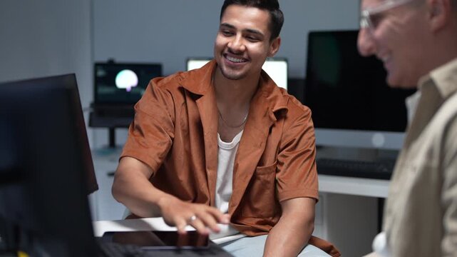 ortrait of a smiling young software developer discussing programming solutions and artificial intelligence parameters with a senior IT consultant.