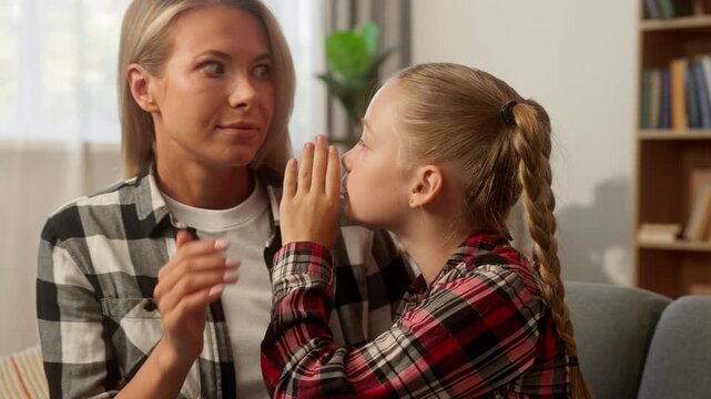Shocked Caucasian mother woman listening daughter whisper gossip sharing secret female family kid at home smiling child little schoolgirl lady mom parent girl talking humour funny story custody laugh