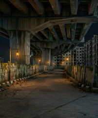 Fototapeta premium Abandoned urban alleyway with vintage street lamps under an overpass, brutalist apartment buildings in the background.