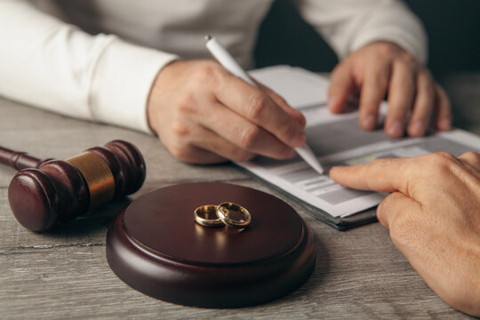 Wedding rings and gavel on divorce decree, closeup