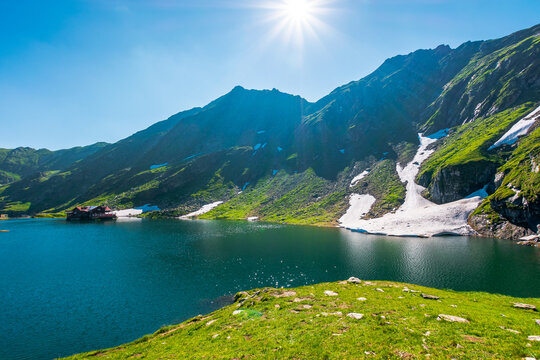 beautiful alpine scenery of fagaras mountains. balea lake in romania mountain landscape. summer weather with clouds on sky. view of rippled water near rocky slope. remote wilderness travel background