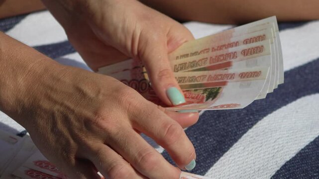 Hands money counting, woman counting Russian 5000 ruble banknotes on a striped blanket