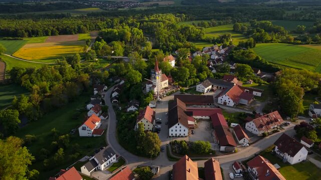 Drone view over Inkofen, Germany, with the Amper River, traditional Bavarian homes, Schloss Inkofen and St. Michael church in summer atmosphere.