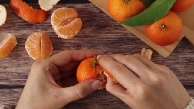 Person is peeling fresh tangerine.