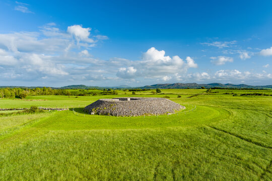 Aerial view of Carrowmore Passage Tomb surrounded by bright green fields in County Sligo, Ireland. An ancient megalithic monument in the Irish countryside.