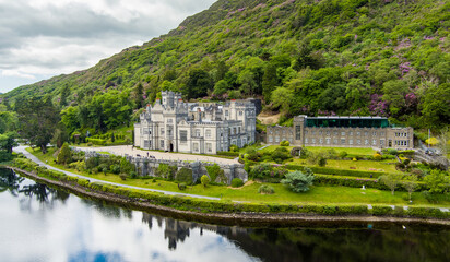Fototapeta premium Aerial view of Kylemore Abbey beside Pollacappul Lough in Connemara, County Galway, Ireland. The estate sits between lake, woodland and mountain slopes.
