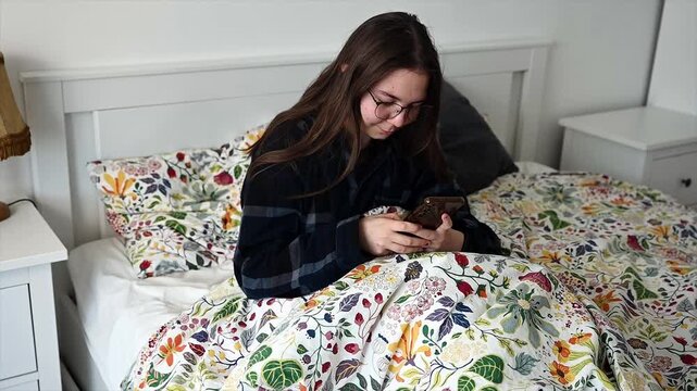 Teen girl lying in bed checking smartphone and scrolling through social media feeds in soft morning light, generation z digital routine and connected lifestyle moment before getting up for school day