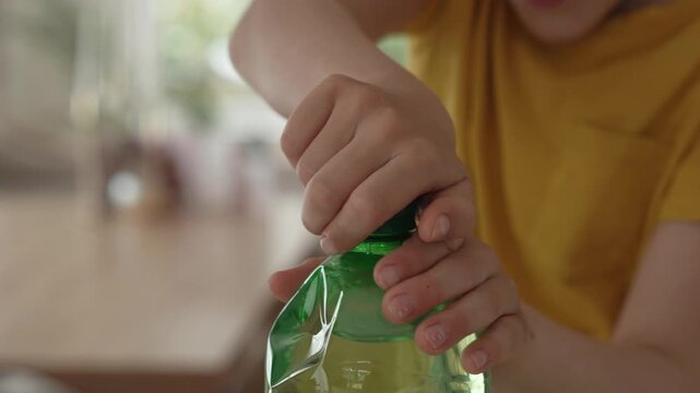 Child unscrewing green bottle cap