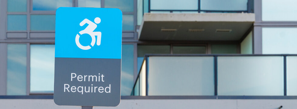Blue permit sign for accessible parking near a modern building