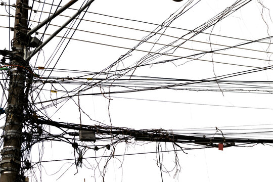 Disorganized electrical grid with multiple tangled cables and urban visual pollution, evoking metropolitan density, improvised technology, and chaotic Brazilian infrastructure.
