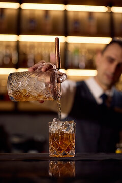 Close up of barmen preparing cold cocktail ice drink at bar counter.