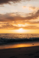 Obraz premium Dramatic golden sunset with sun rays over Pacific Ocean and surfer silhouettes