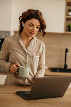 Woman holding a mug, using laptop computer for a video call