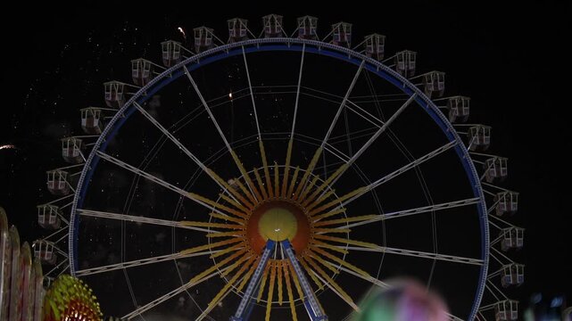 Munich, Germany. Fireworks burst over the Theresienwiese in Munich, Germany, as crowds enjoy the spring festival with bright lights, music, and amusement rides.