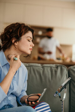 Woman applying makeup during morning routine at home