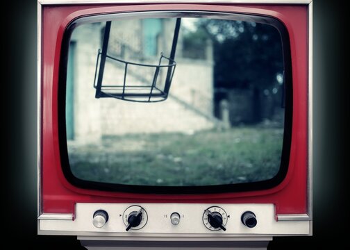Vintage red television displaying eerie swing set scene with unsettling atmosphere. Retro TV screen shows haunting playground imagery. For horror, thriller, and nostalgic suspense concepts.
