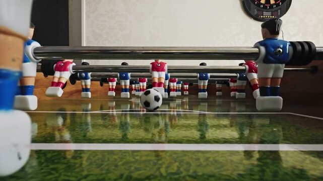 Slow motion: Low angle point of view shot inside a foosball table as the ball rolls directly into the camera lens