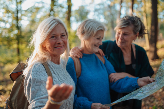 Mature female friends exploring nature together with map on hiking trip.