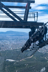 Fototapeta premium Close up of a cable car roller assembly and steel cable with a distant city valley background.