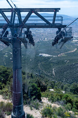 Fototapeta premium High angle view from a cable car cabin looking down at a massive steel support tower and a distant city valley.