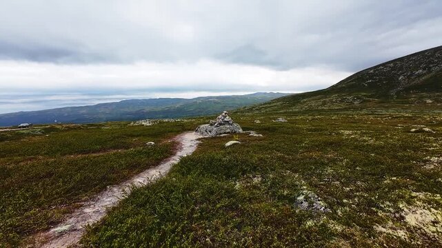 Aerial flight over Norwegian mountain plateau revealing cairn and cabins
