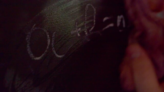 Close up of hand erasing math formula A plus B equals AB from chalkboard.A macro shot with shallow depth of field showing a hand wiping away an incorrect mathematical or chem