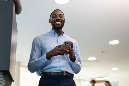 Smiling african american businessman using smartphone in office