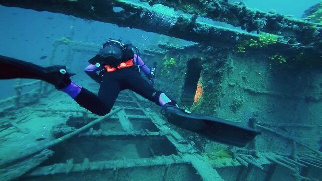 Advanced Diver Gliding in Zero Gravity Through Sunken Ship Wreckage.  The calm, professional diver glides effortlessly through the historic deep-sea wreckage at forty meters depth. Adventure lifestyle