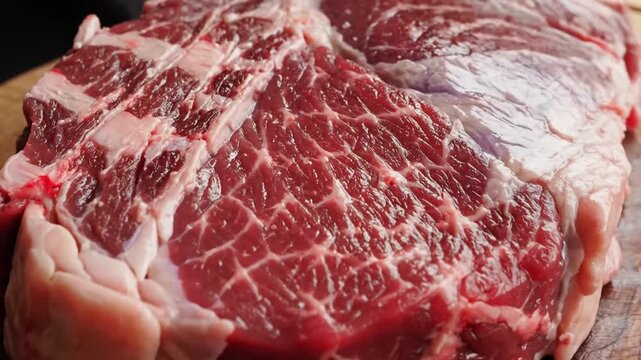 Close-up of marbled raw beef cuts on a wooden surface showcasing texture and freshness