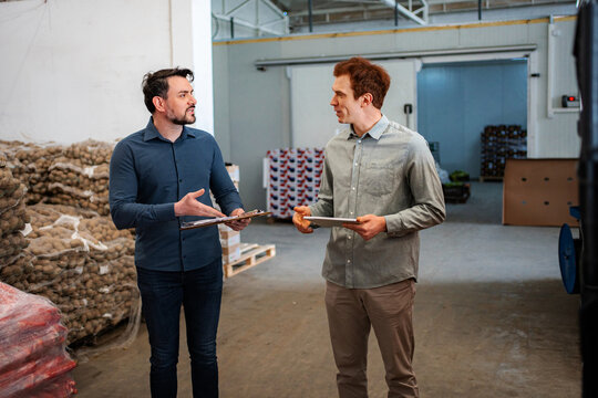 Business partners discussing inventory in a productive warehouse