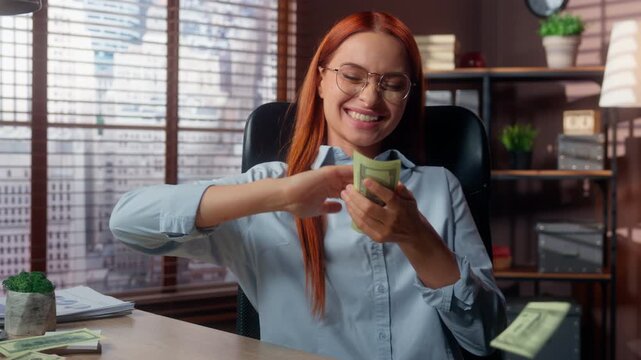 Happy carefree Caucasian business woman throwing cash money rain at office table excited rich businesswoman throw salary banknotes joyful female girl executive fooling around with finance in company