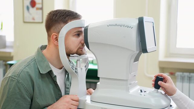 Male patient undergoing eye examination with autorefractor